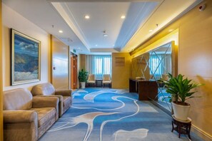 A hotel lobby with a reception desk, seating area, and a large mirror reflecting the interior. - Ordos Aili Hotel (Beijing Jinbao Street) (Beijing)