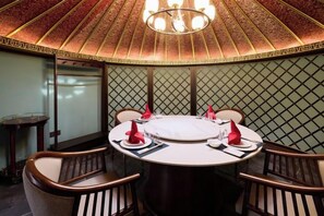 A round dining table with chairs, a chandelier, and a patterned wall. - Ordos Aili Hotel (Beijing Jinbao Street) (Beijing)
