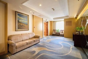 A hotel lobby with a beige sofa, a large painting, a patterned carpet, and a reception desk. - Ordos Aili Hotel (Beijing Jinbao Street) (Beijing)