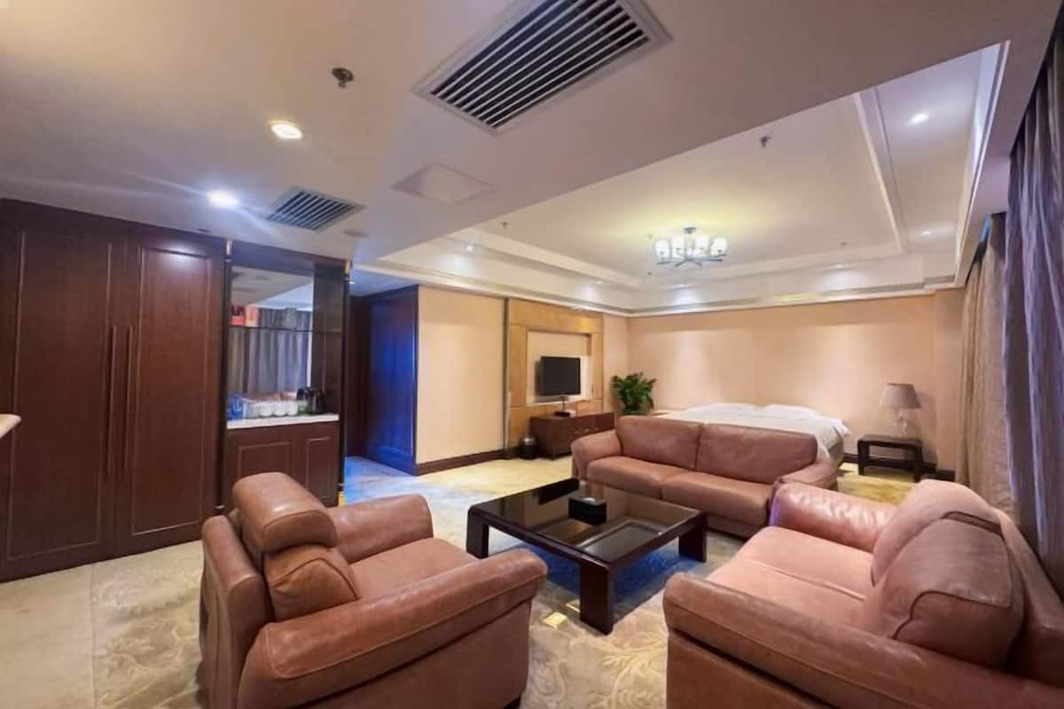 Una habitación de hotel con sofá, mesa de centro, televisor y cama.