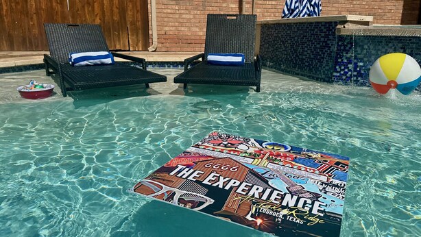 Een zwembadgedeelte met ligbedden, een strandbal en een tijdschrift dat drijft.