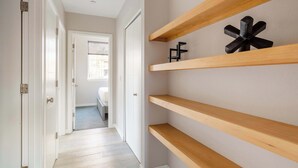 Un couloir avec des étagères en bois et un objet géométrique noir accroché au mur.