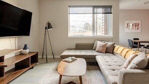 Un salon moderne doté d’un grand téléviseur à écran plat, d’un canapé, d’une table basse et d’un coin repas avec des chaises.