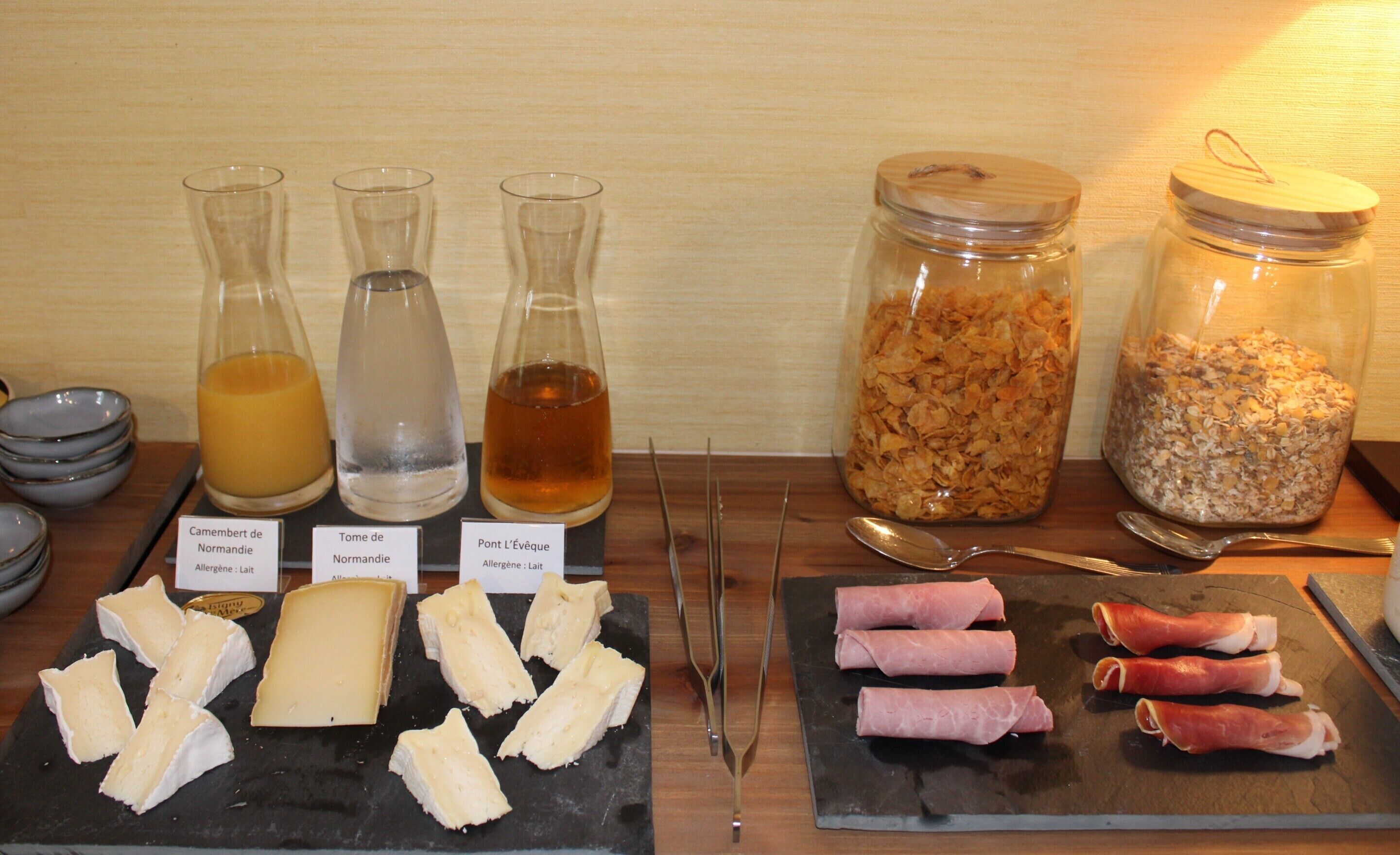 A buffet setup with cheese, ham, and various beverages.