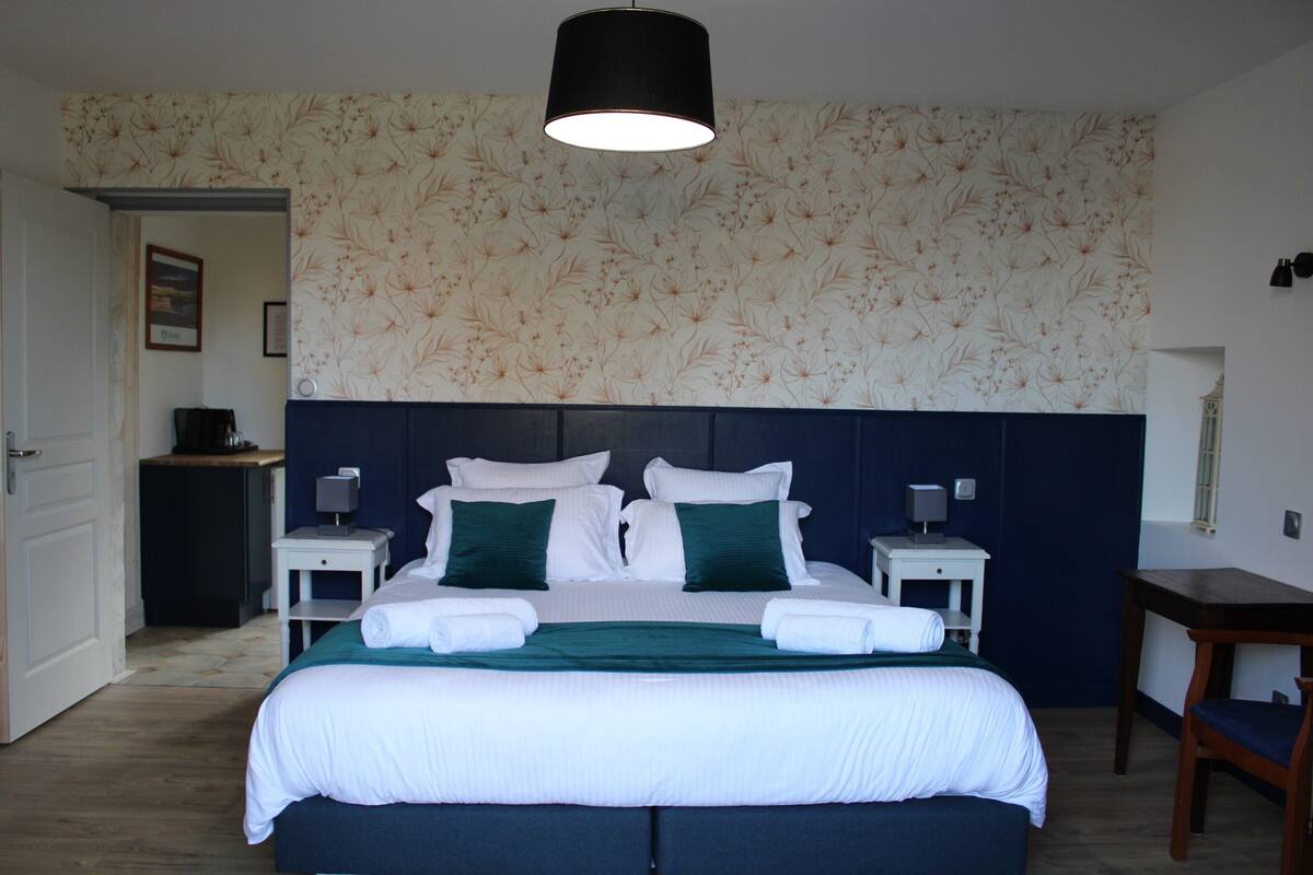 A hotel room with a large bed, two bedside tables, a desk, and a chair.
