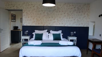 Una habitación de hotel con una cama grande, dos mesitas de noche, un escritorio y una silla.