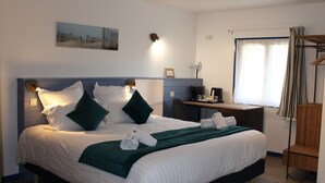 A neatly made bed with white and green bedding, a desk with a computer, and a window with curtains. - Domaine des Piéris  (Grandcamp-Maisy)
