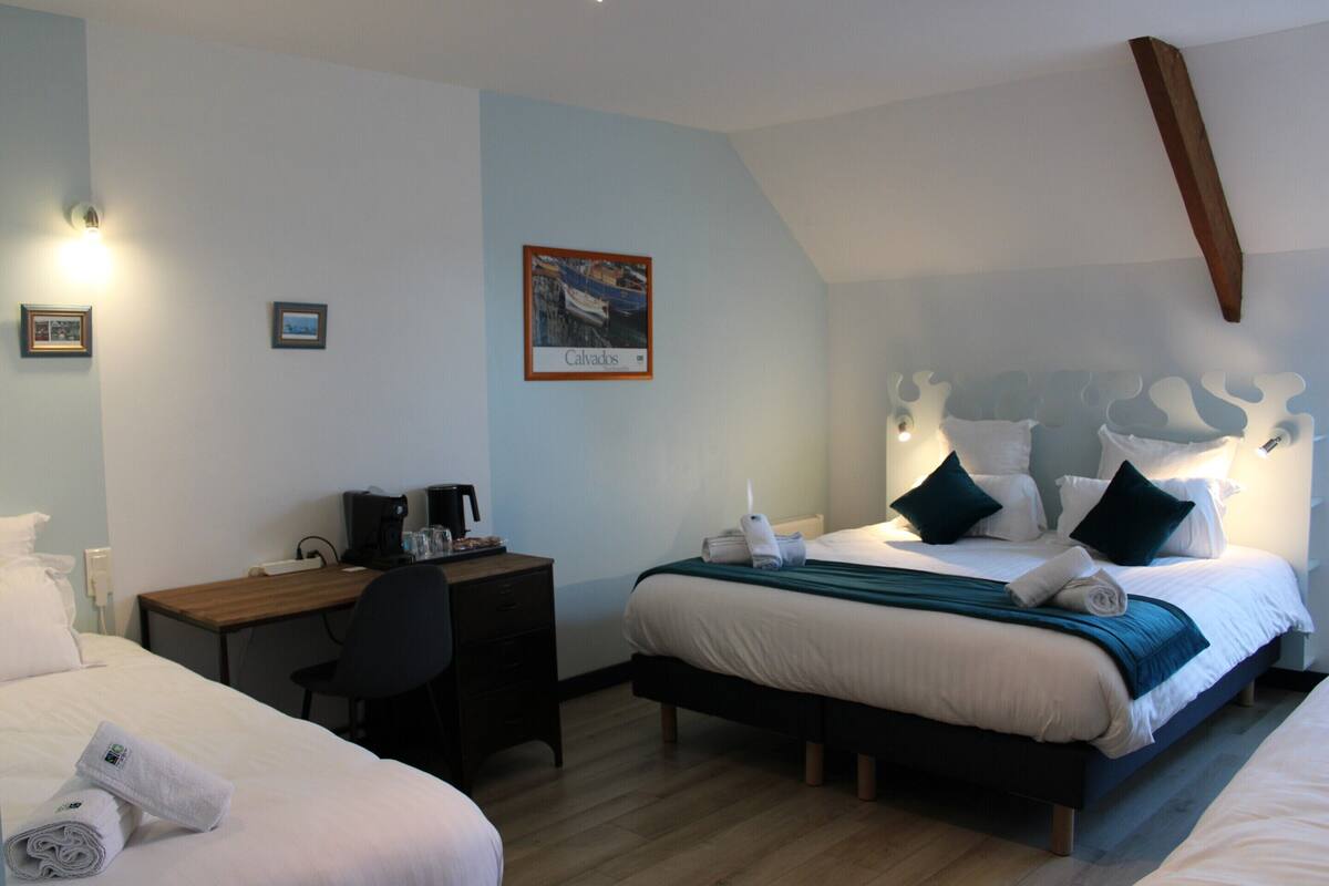 A hotel room with two beds, a desk, and a chair. There is a framed picture on the wall and a wooden beam above the bed.