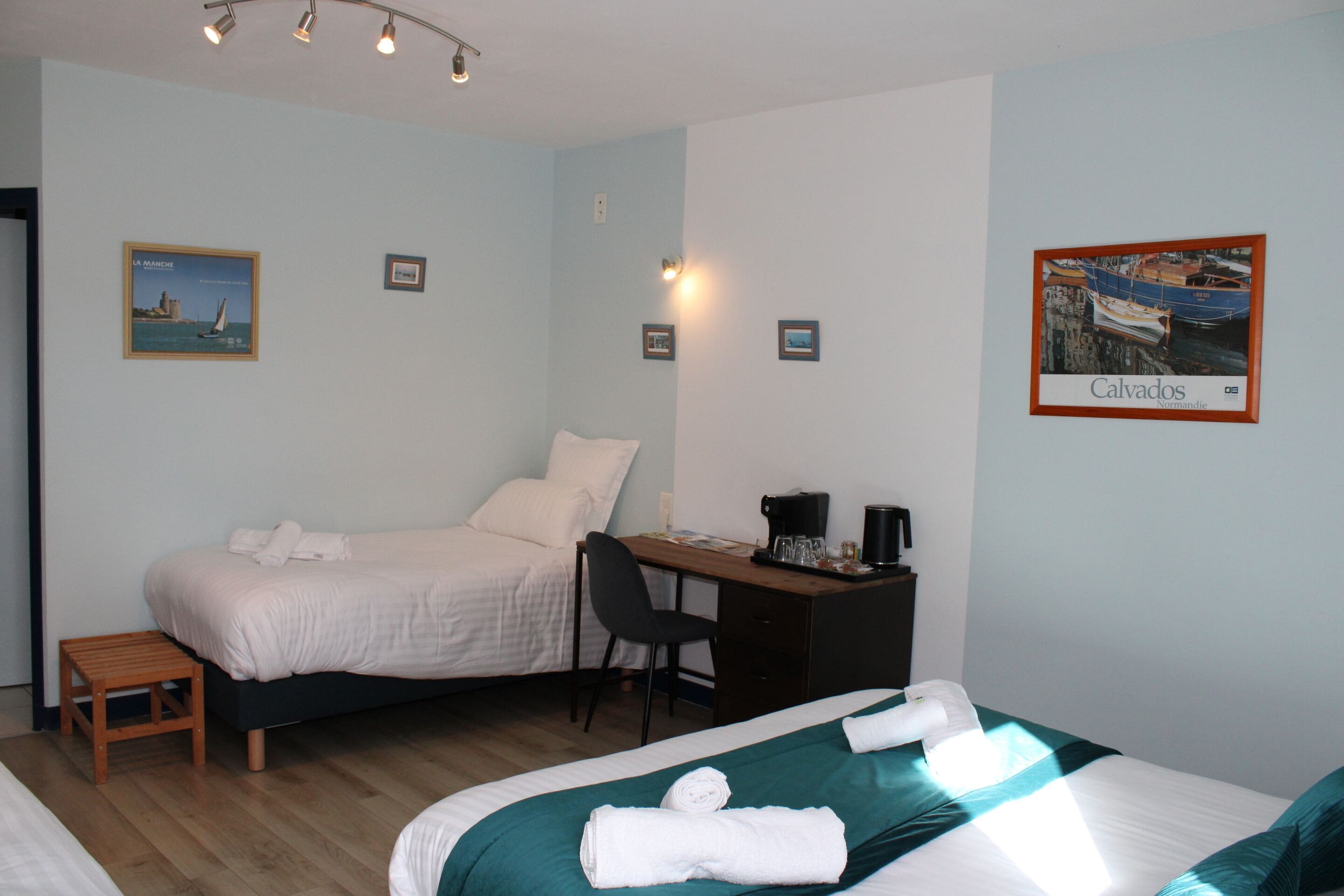 A hotel room with two beds, a desk, a chair, and a small table.