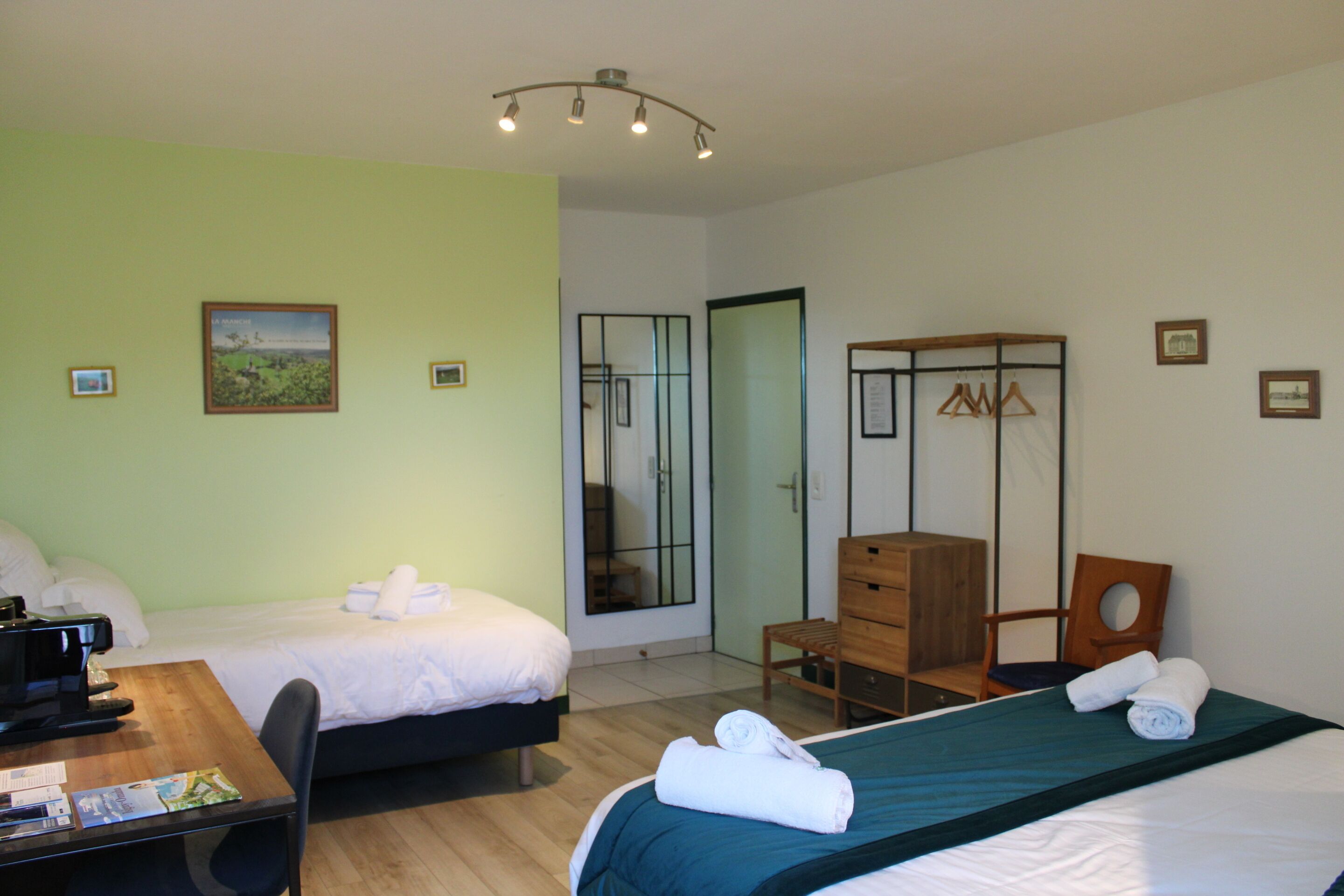 A hotel room with two beds, a desk, a chair, a dresser, and a mirror.