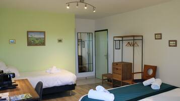 Quarto de hotel com duas camas, uma escrivaninha, uma cadeira, cômoda e um espelho.