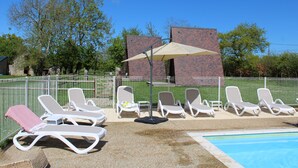 A poolside area with sun loungers and a brick building in the background. - Domaine des Piéris  (Grandcamp-Maisy)