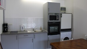 A compact kitchen with a microwave, oven, and washing machine, a sink, and a coffee maker. - Domaine des Piéris  (Grandcamp-Maisy)
