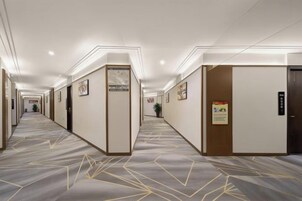 A hotel corridor with doors, framed pictures, and a carpeted floor.