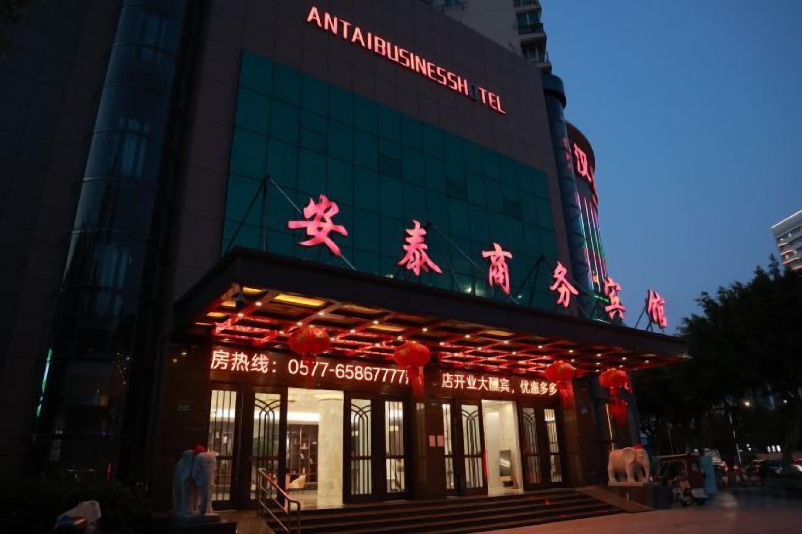 A building with a large sign for 'ANTAI BUSINESS TEL' and another sign for '安泰商外安' with a staircase leading to the entrance.