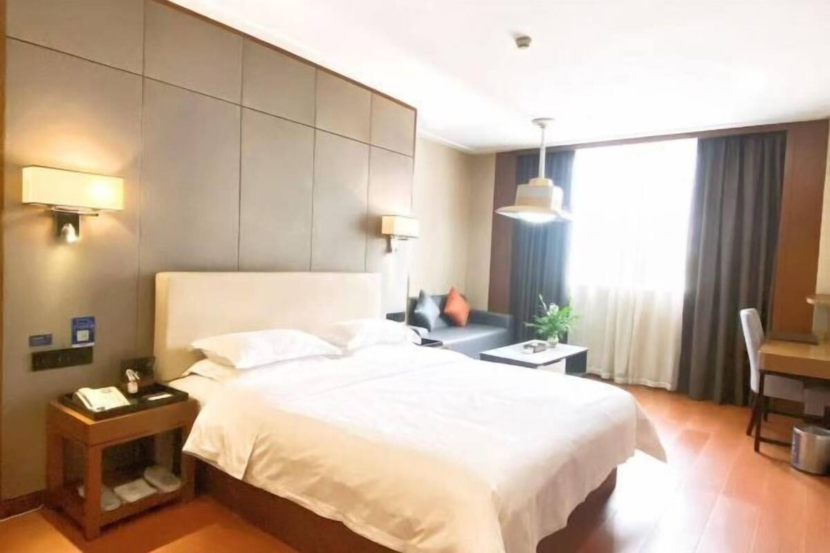 Een hotelkamer met een groot bed, nachtkastjes, een bureau en een stoel.