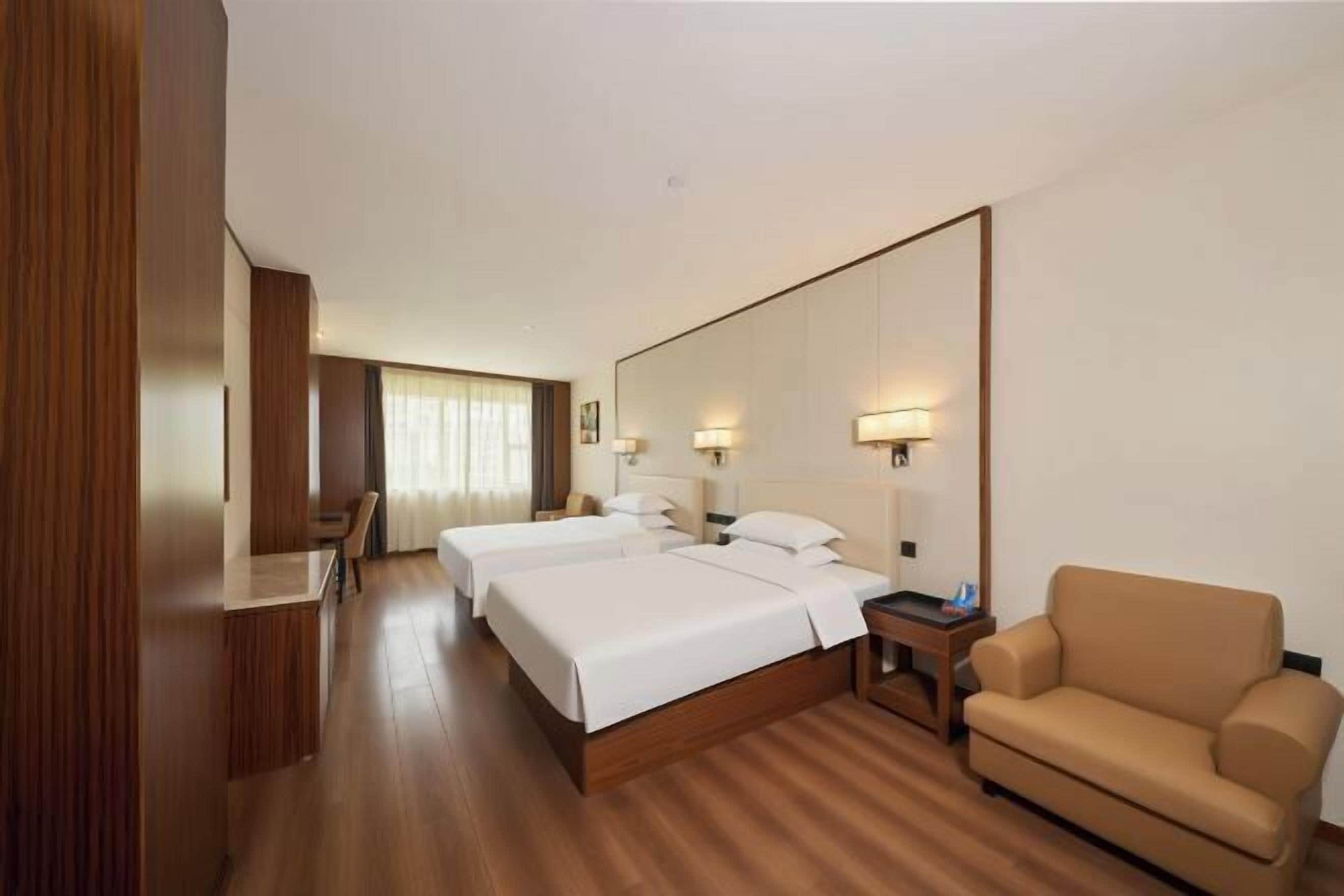 Una habitación de hotel con una cama grande, un escritorio, una silla y un sofá.