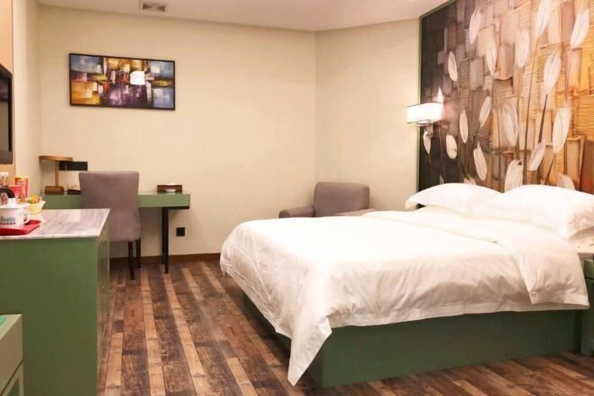 Een hotelkamer met een bed, een bureau, een stoel en een schilderij aan de muur.
