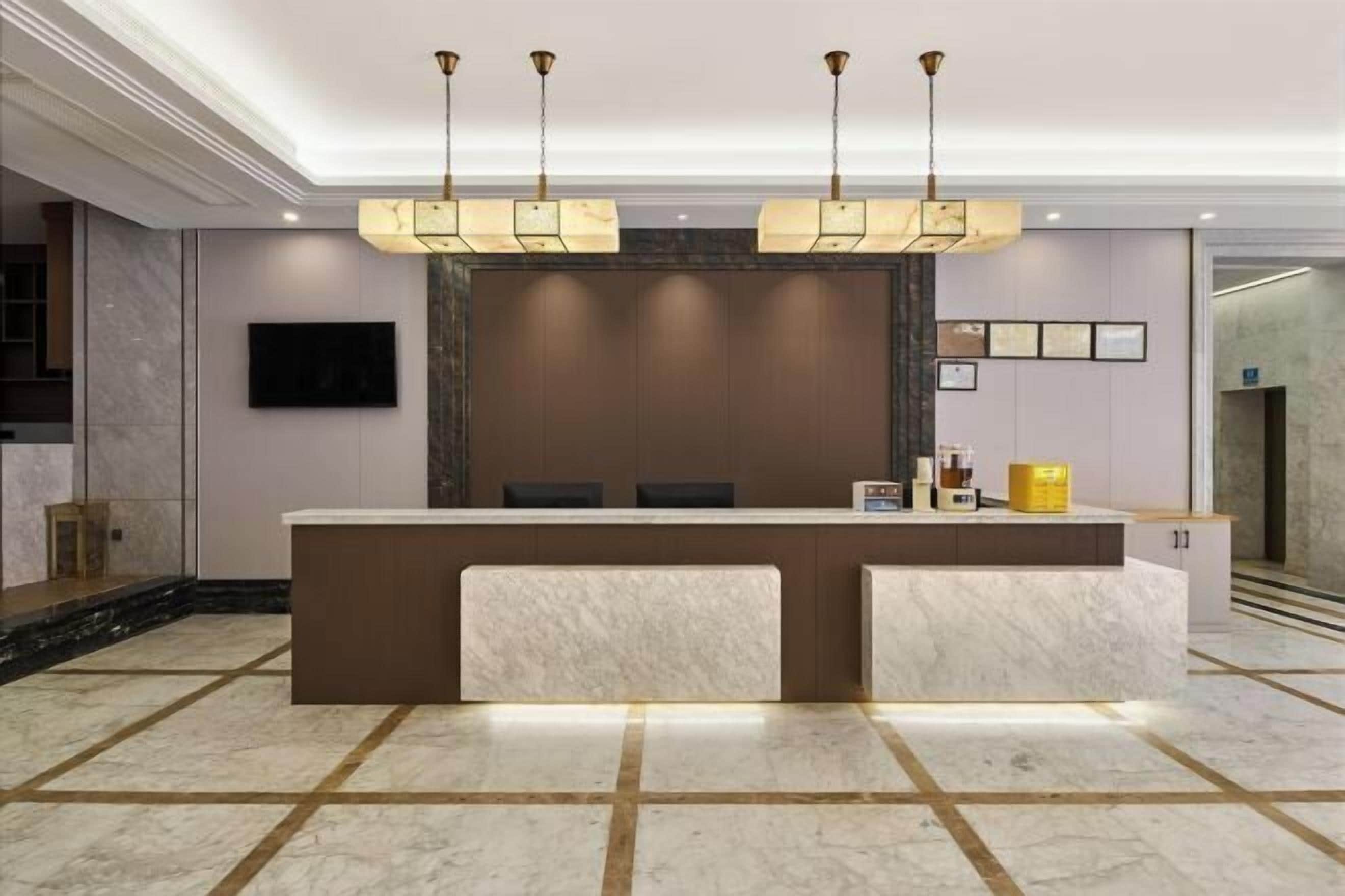 A reception area with a marble counter, a flat-screen TV, and a modern chandelier.