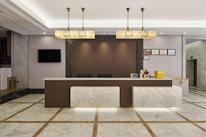A reception area with a marble counter, a flat-screen TV, and a modern chandelier.