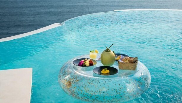 A clear view of a swimming pool with a floating table set up on the water, containing food and drinks. - Private Jet Villa Uluwatu (Bali)