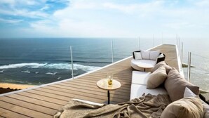 A deck with a sofa and a small table, overlooking the ocean. - Private Jet Villa Uluwatu (Bali)