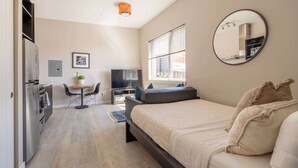 Ein modernes Schlafzimmer mit Bett, Fernseher, kleinem Tisch und einer Couch.