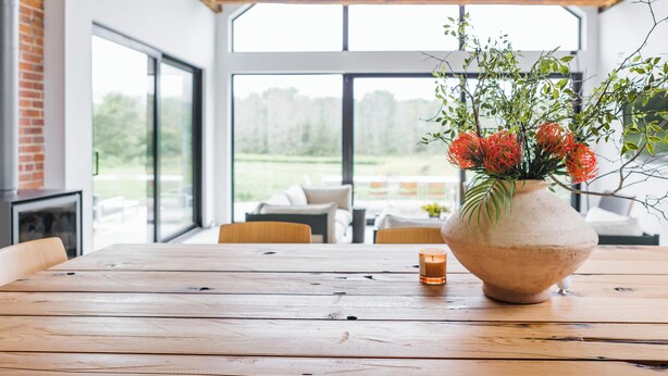 A wooden table with a vase of flowers and a candle.