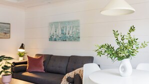 Un salon moderne avec un canapé gris, une table ronde blanche et une plante en pot.