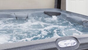 Un bain à remous avec une paroi extérieure en bois et une porte blanche en arrière-plan.