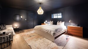 A bedroom with a large bed, bedside tables, a round mirror, and a hanging light fixture. - The Willows | 3 Bedrooms | 6 Guests | Heated Pool (Prince Edward)