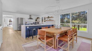 A modern kitchen with a central island, white cabinetry, and a large window offering a view of the outdoors. - The Willows | 3 Bedrooms | 6 Guests | Heated Pool (Prince Edward)