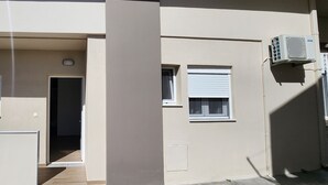 Um corredor com duas janelas, uma com persiana fechada e um ar condicionado fixado na parede.