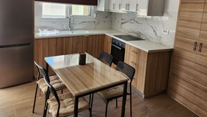 Cozinha moderna com área de refeições, apresentando bancada de mármore, armários de madeira e forno embutido.