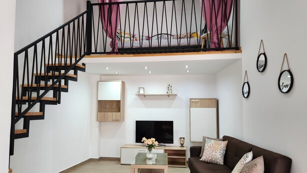 Uma sala de estar moderna com escada, sofá, mesa de centro e televisão.