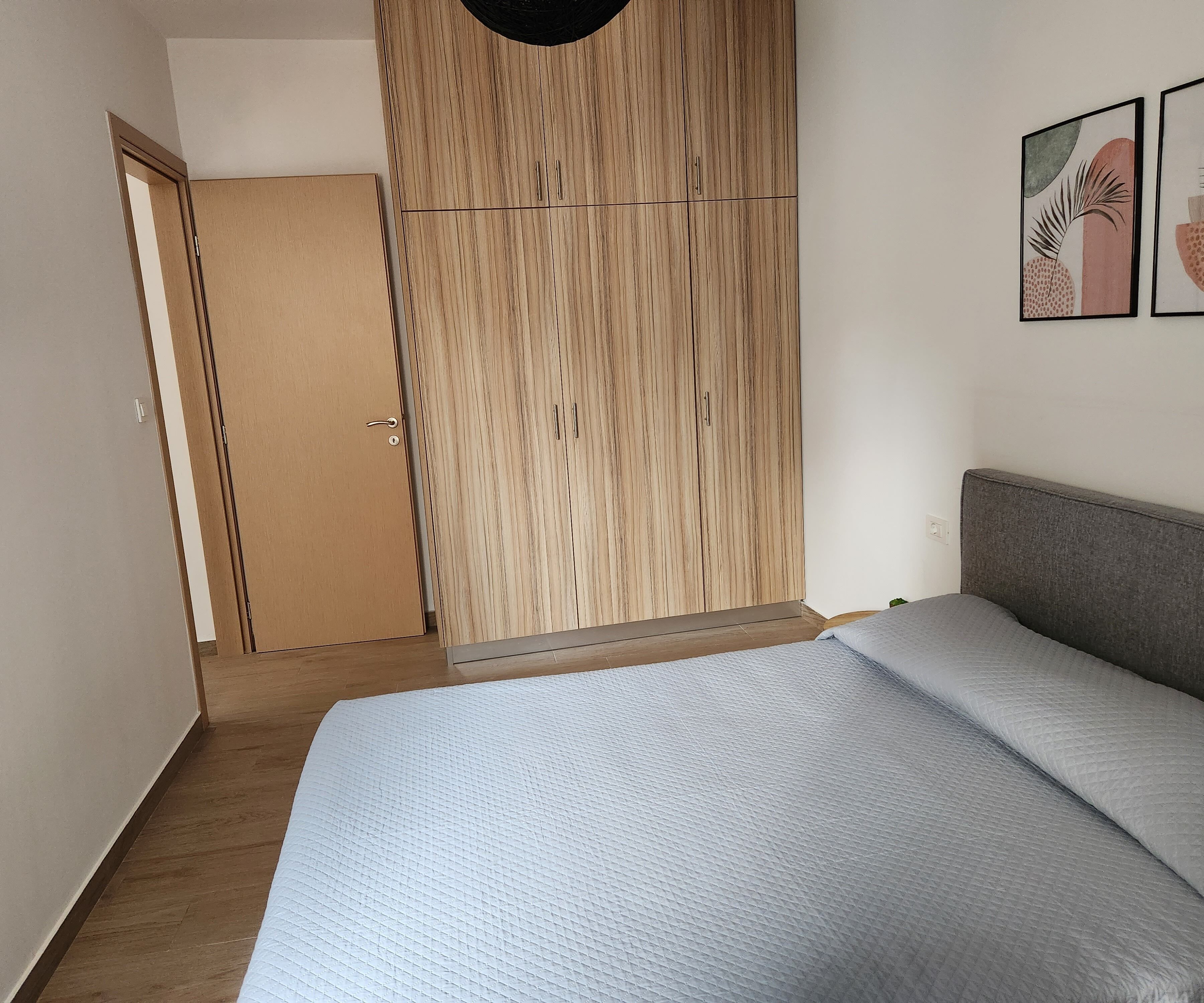 A bedroom with a bed, a wardrobe, and a door leading to another room.