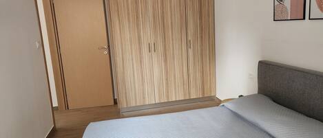 A bedroom with a bed, a wardrobe, and a door leading to another room.