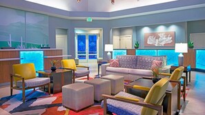 A lobby with a reception desk, seating area, and a large window with a view.
