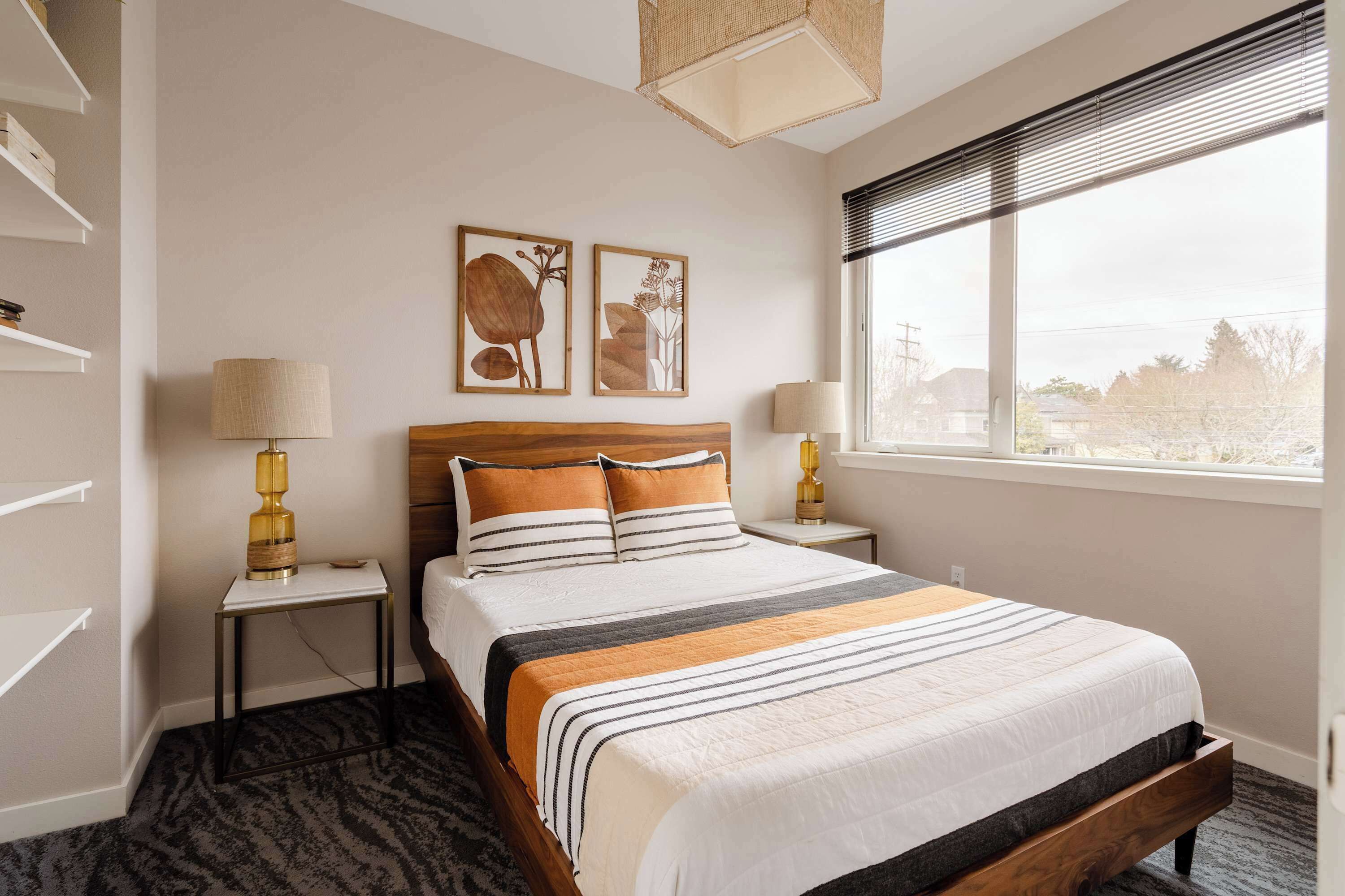 Quarto bem organizado com cama, mesas de cabeceira e obras de arte na parede.