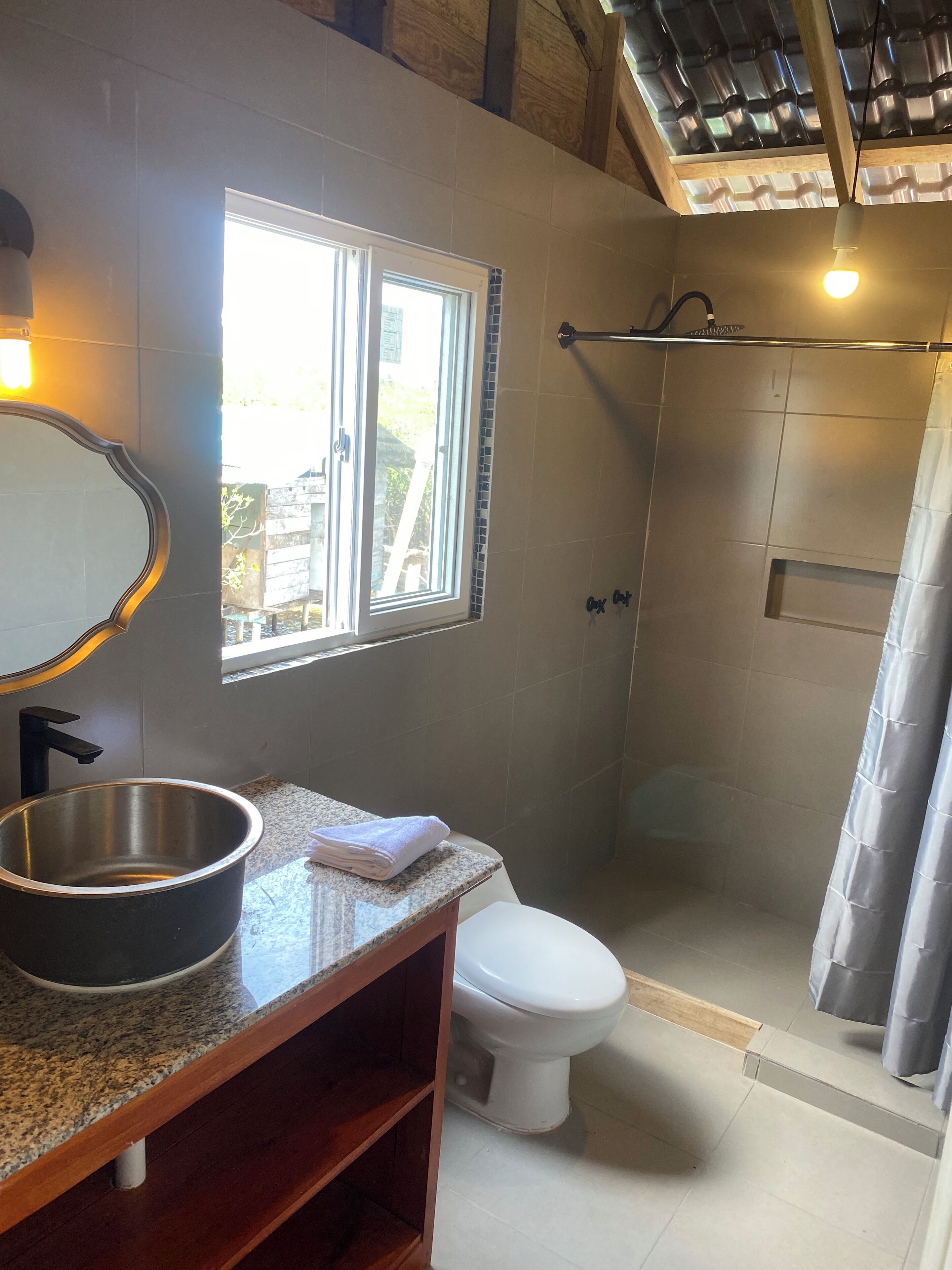 Une salle de bain avec un comptoir en granit, un lavabo, un miroir, des toilettes et un espace douche.