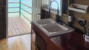 Una cabaña de madera con zona de cocina, que incluye un lavamanos y armarios, y vista al agua.