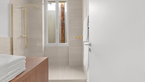 A modern bathroom with a glass-enclosed shower, a wooden vanity, and a towel rack. - Renovated Apartment Min. from Beach/Palais (Cannes)