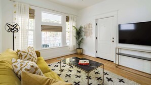 A living room with a sofa, a coffee table, a TV, and a ceiling fan.