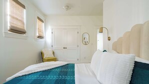 A bedroom with a bed, a chair, a wardrobe, and a mirror.