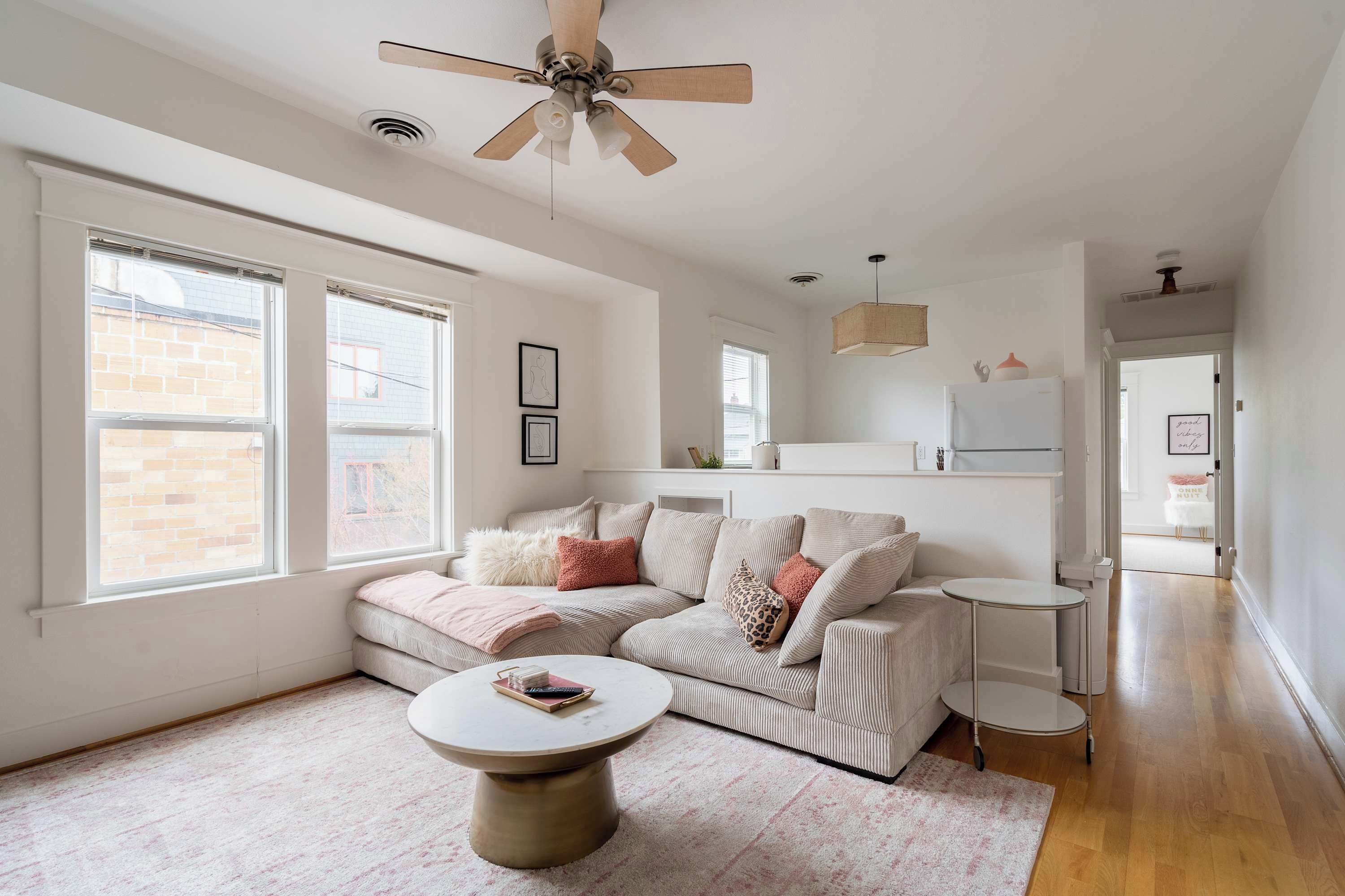 A modern living room with a sectional sofa, a coffee table, and a ceiling fan.