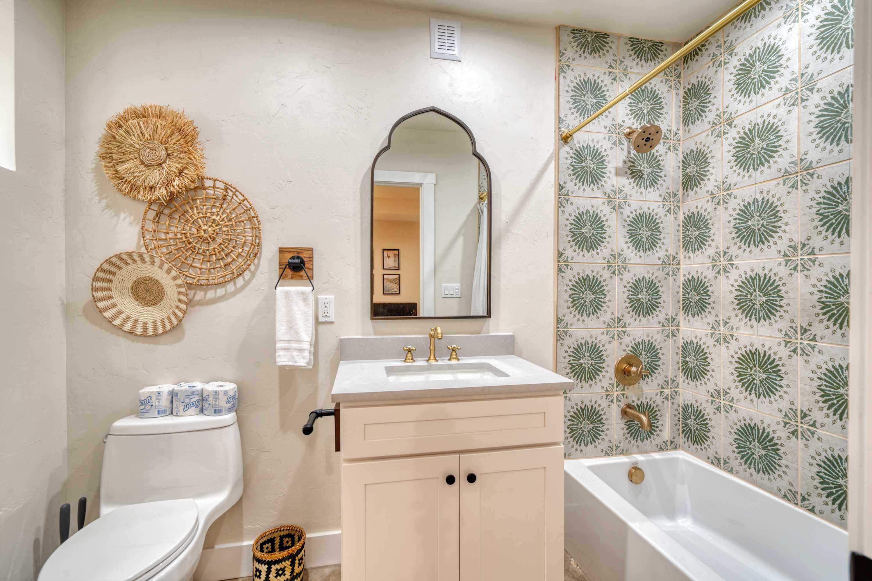 A bathroom with a toilet, sink, vanity, and bathtub.