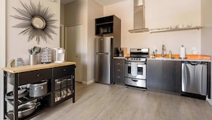 Eine moderne Küche mit Einbauofen, Mikrowelle und Geschirrspüler. Es gibt eine Holz Arbeitsplatte und einen schwarzen Schrank mit Glastüren.