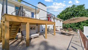 A covered outdoor area with a wooden deck, a staircase, and a seating area with chairs and a sofa. - Poolside Paradise-Kayaks/SUPs, Private Pool, Billiards, Foosball (Winchester)