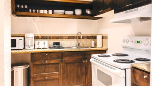 Cozinha compacta com micro-ondas, torradeira, cafeteira e fogão.