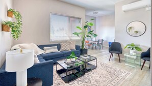 Un salon moderne avec un canapé bleu, une table basse en verre et une grande plante en pot.